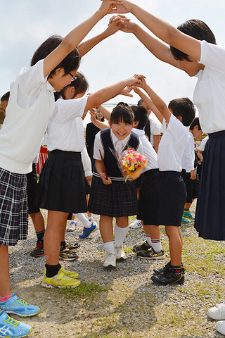 在校生の花道を笑顔でくぐり抜け、母校を後にする明石小学校の鈴木媛香さん＝20日午前、同校