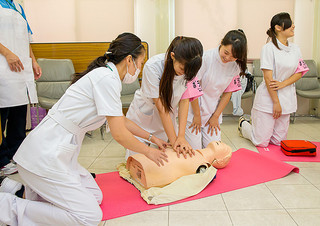 かりゆし病院の「ふれあい看護体験」で、人形を使って心肺蘇生を体験する高校生ら＝13日午後、同病院