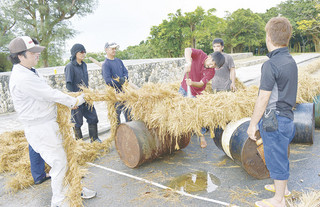 大綱を作る「ツナマカシ」で、金属バットでたたきながら綱を締める作業を行う大浜地域の住民ら＝18日午後、崎原道路