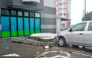 ホテルの外壁が崩れ落ち、敷地内駐車場に止めてあったレンタカーのフロント部分が破損した＝７日午後、市内八島町