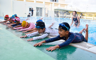 夏休み水泳教室でバタ足の練習をする児童たち＝10日夕、平真小学校プール
