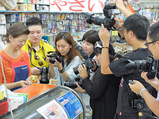 知念秀子常務から人気の「オニササ」について取材する台湾のメディア関係者ら＝７日午前、字登野城の知念商会本店
