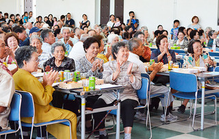 大浜公民館の敬老祝賀会で、多彩な余興に見入り、拍手を送る高齢者たち＝23日午後、同館
