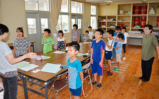 クラブ活動「英会話」の時間に英語版の校歌を歌う大本小学校の児童たち。右は英訳した漢那ひとみ校長＝９日午後、同校