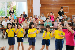 演奏後、大川婦人会の女性と一緒に踊りを披露する登野城小器楽クラブの児童ら＝10月31日午前、大川公民館
