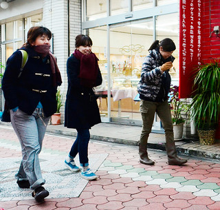この冬一番の寒さに厚手の服を着込んで歩く人々＝24日午後、石垣市美崎町