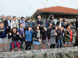 復興への思いを託して風船を大空に放つ園児と参列者ら＝11日午後、新栄公園