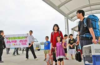 黒島に降り立った吉山医師一家と、歓迎に駆け付けた黒島校の児童生徒ら＝18日午後、黒島港。