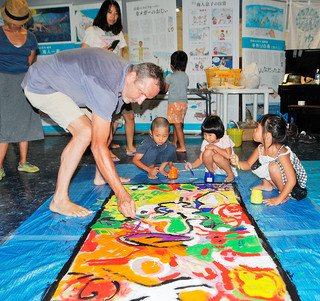 アート作品をつくるワークショップで演出家・美術家のダリオ・モレッティさん（左）と絵を描く子どもたち＝27日午前、石垣港離島ターミナル内のとぅもーるネットセンター石垣