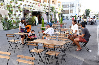 美崎町の通りをオープンカフェにして昼間のにぎわいを創出する社会実験で飲食を楽しむ人々＝19日午後、石垣島ヴィレッジ前の市道