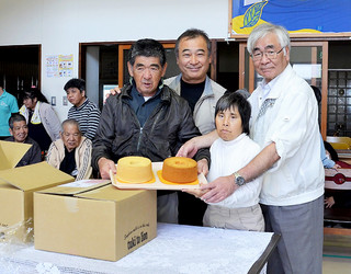 大澤邦昭氏（右）とともにシフォンケーキの贈呈を喜ぶ利用者ら＝16日午後、育成園玄関ホール