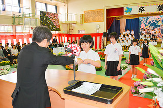 登野城小学校の卒業式で、浦崎喬校長（左）から笑顔で卒業証書を受け取る卒業生＝23日午前、同校体育館