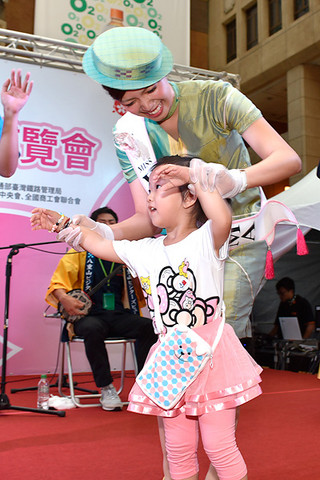 特設ステージで行われたモーヤーで、台湾の子どもと一緒に踊るミス南十字星の大久奈織さん＝24日午後、台湾・台北市の台北駅