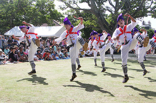 竹富島最大行事「種子取祭」の２日間の奉納芸能が幕開け。勇ましい掛け声とともに力強く跳びはねる「馬乗者（ンーマヌシャ）」に盛大な拍手が送られた＝30日午前、世持御嶽