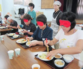 アイマスクをしての食事を体験する参加者ら＝上原多目的施設