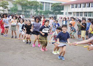 チャレンジデーの取り組みとして大縄跳びに挑戦する子どもたち。笑顔が広がった＝29日午後、登野城小学校