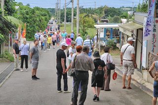 徒歩で移動する大勢の観光客。その間を縫うようにレンタカー（奥）が通行する＝５月15日午後、米原のヤエヤマヤシ群落