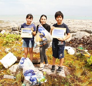 真栄里海岸で８月の１カ月間、調査を兼ね海岸清掃を行った一般社団法人ビーチクリーンロボットプロジェクト海岸工学会会員のはやのん氏（中央）ら＝６日午後、同海岸