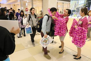 初便で到着した客をピンクの花をかたどったレイで歓迎するピーチ・アビエーションの客室乗務員ら＝26日夜、南ぬ島石垣空港