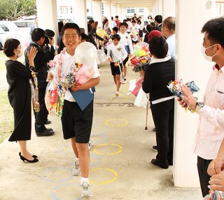 宮良小学校で卒業式を終え保護者らの祝福を受けながら退場する卒業生ら＝20日午前、同校