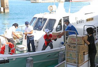 生活必需品を船に積み込む事業者ら＝３日午後、石垣港離島ターミナル