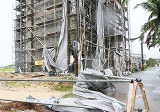 建設中の建物のシートが強風ではがれ、付近の電柱やフェンスに絡まった＝３日午前、石垣市真栄里