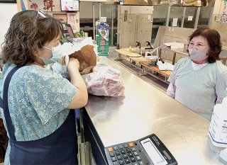 公設市場で旧正月用の豚肉などを買う女性（右）＝11日午後