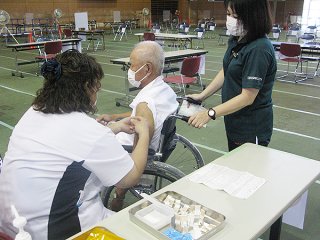 高齢者を対象とした新型コロナウイルスワクチン接種を受ける人＝17日午後、市総合体育館メインアリーナ