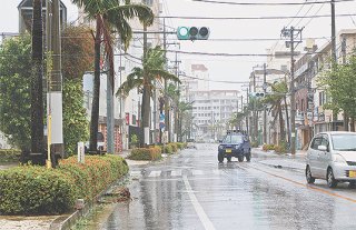 台風の接近に伴い暴風が吹き荒れた市街地。街路樹が折れたり停電で止まる信号があった＝23日午後、市役所前