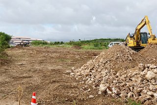 重機を使った伐開工事が始まった旧空港跡地線。奥には石垣市役所新庁舎が見える＝6日午後
