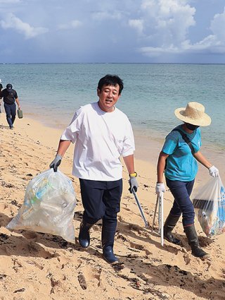 ペットボトルが入ったごみ袋を運ぶ前田亘輝さん＝7日午前、西表島中野海岸