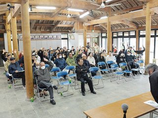 温泉リゾート施設に挙手で反対の意思を示す住民ら＝24日午後、竹富島まちなみ館