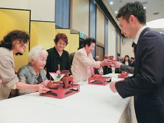 あやかりの盃を授ける左から97歳カジマヤーの漢那文江さん、豊見山キクさん＝18日午後、アートホテル石垣島