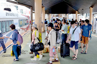 竹富町内の各離島に向かうため高速船に乗り込む観光客ら＝12日午後、石垣港離島ターミナル