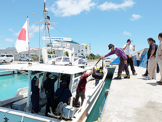 石垣海上保安部の立ち入り検査が行われる中、漁船に荷物を積み込む仲間均氏（右側）ら＝25日午後１時前、登野城漁港