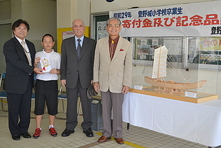 母校の登野城小学校に50万円とサバニ帆船の模型を贈った「記念品を贈る会」の松本淳代表（右）と製作した青山武次さん（その左）＝３日午後、同校