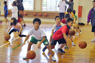 バスケットボール教室でドリブルの指導を受ける子どもたち＝21日午後、大原中学校体育館