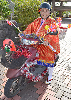 カジマヤーの衣装を着てミニバイクにまたがる下里さん＝１月31日午後、市民会館前