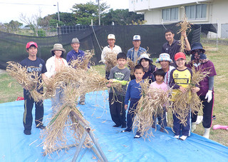 刈り取った麦を手にする黒島の子どもたちと黒島老人クラブの人たち＝18日、同校