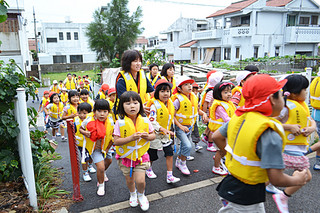 避難訓練で真栄里公園に向けて走る八島小学校の児童ら＝24日午前、同校近くの避難道路