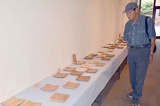 戸眞伊さんが58種の島材を使って製作した角皿などに見入る参観者
＝20日午後、石垣市民会館展示ホール
