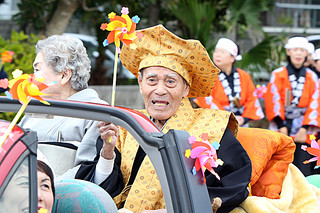 97歳のカジマヤーを迎え、パレードで祝福を受ける山城清有さん＝２日午前、平得公民館近く