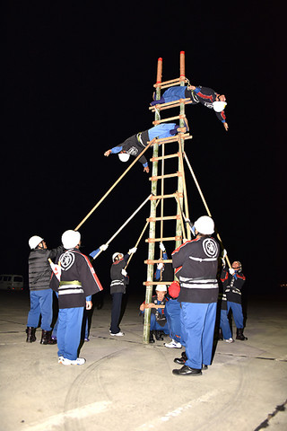 消防出初式に向け、寒空の下ではしご乗りの練習をする市消防団員ら＝９日夜、市消防本部