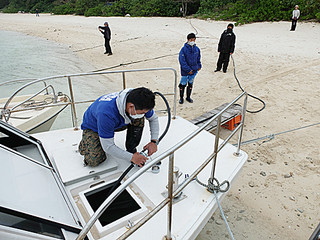 ケーブルを使ってＥＶ船に充電する作業員。フル充電には４時間余もかかるという＝１月31日午後、川平湾