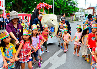 釈迦像を乗せた白象の台車を引きパレードに出発する子どもたち＝７日午後、市内石垣
