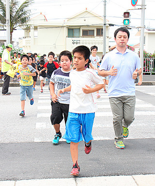 津波注意報を受け、一時避難所の真栄里公園に向かう八島小学校の児童ら＝20日午前、真栄里公園前の横断歩道