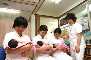 ふれあい看護体験で緊張しながらも、新生児を抱いて笑顔をみせる生徒たち＝l5日午後、八重山病院