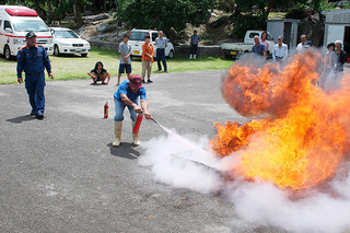 防災訓練で消火器の取り扱い訓練をする住民ら＝17日午後、伊野田集落センター