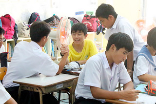 石垣第二中学校の生徒と腕相撲をする陳子元君＝16日午後、同校教室