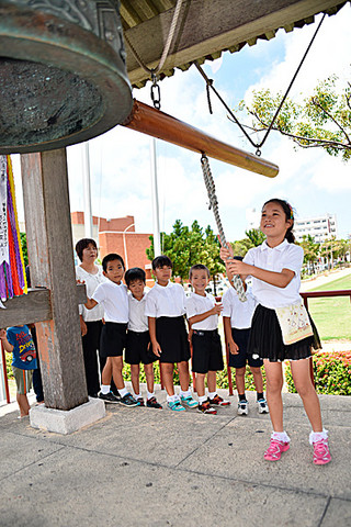 世界平和の願いを込めて平和の鐘を打ち鳴らす子どもたち＝新栄公園内の世界平和の鐘鐘楼